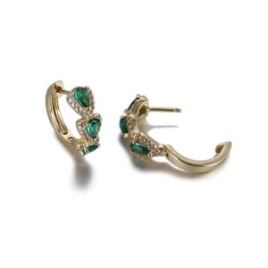 Détail de boucles d'oreilles dorées avec pierres vertes taille poire et zircons