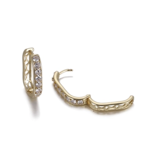 Détail de boucles d'oreilles créoles dorées avec zircons blancs et maille évidée