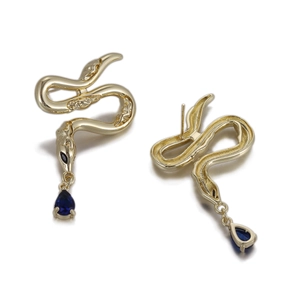 Détail de boucles d'oreilles serpent dorées avec pendentifs en pierres bleu foncé