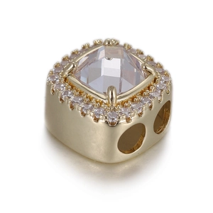 Macro detail of square gold charm with clear faceted center stone and pavé setting