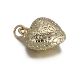 Detailed close-up of golden heart pendant with floral embossing and metal ring
