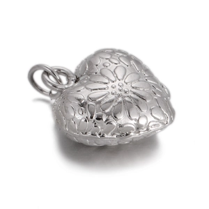 Close-up of heart-shaped silver pendant with floral embossing and metal connector ring