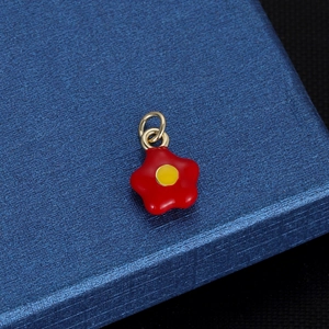 Pendentif mignon fleur rouge avec anneaux dorés sur une boîte à bijoux bleue