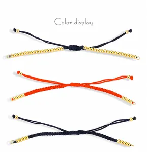 Detail von handgewebten Armbändern in Blau und Orange mit Goldperlen und Gleitknoten