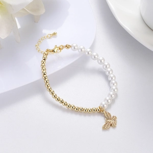 Detail of beaded bracelet featuring white pearls, gold beads, and a crystal butterfly charm