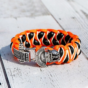 Detail van paracord survival armband met een vintage metalen schedel gesp op houtoppervlak