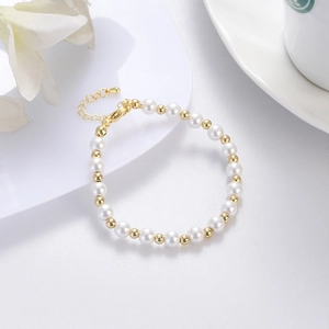 Eleganteres Perlenarmband mit goldfarbenen Perlen und verstellbarem Verschluss auf Porzellan