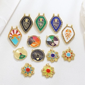 Close-up of 18k gold-plated Hamsa hand and tarot style enamel pendants with zircons