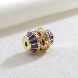 Macro view of vintage gold barrel bead with purple enamel and red marquise crystals