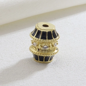 Macro shot of gold barrel bead with black enamel and marquise zircon inlay