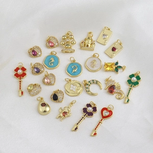 Vue macro de divers pendentifs DIY plaqués or 18k avec clés émaillées et cœurs en zircon