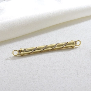 Macro detail of a gold cylindrical pendant with spiral inlaid white rhinestones and rings