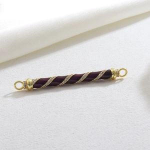 Macro view of purple enamel barrel charm with gold spiral and cubic zirconia inlay