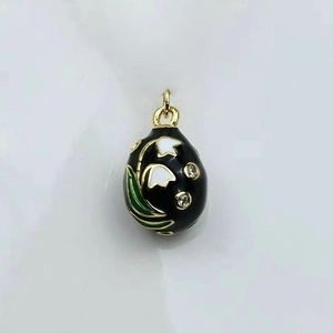 Detail of vintage black enamel egg pendant featuring white lily of the valley and gold clasp