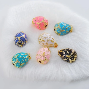 Close-up of Faberge-style enamel egg pendants with gold vine patterns and rhinestones