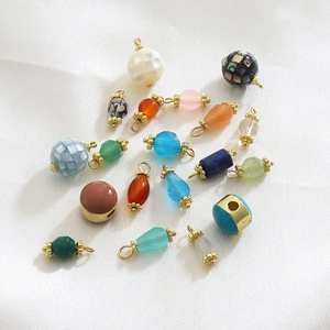 Detailed macro view of assorted natural stone pendants on elegant white silk fabric background