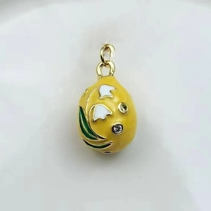 Detailed close-up of a yellow enamel egg pendant with white lily of the valley and gold trim