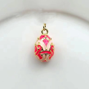 Macro shot of a 18k gold-plated Russian egg pendant with red and pink enamel details