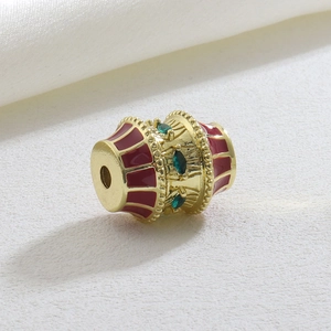 Macro detail of luxury geometric gold charm with red enamel and green marquise zircons