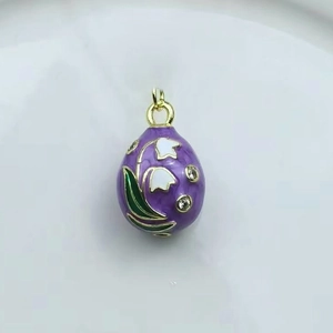 Detail of purple enamel egg pendant featuring lily of the valley and 18k gold accents