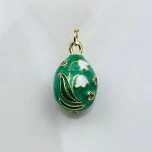 Detailed macro view of green enamel egg pendant with lily of the valley floral pattern