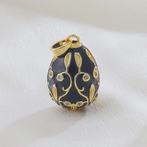 Macro view of Faberge style egg pendant with black enamel and gold floral details