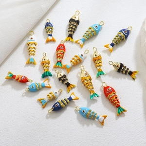 Vue macro d'un pendentif poisson en émail coloré avec écailles dorées et articulées