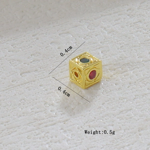 Vista macro detallada de un dije de cubo chapado en oro de 18k con piedras preciosas