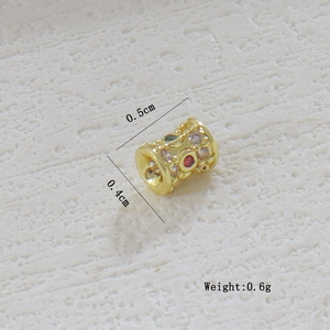 Detalle de un dije calado chapado en oro de 18k con piedras preciosas y dimensiones