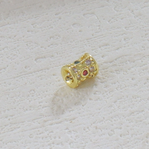 Detalle macro de cuenta espaciadora bañada en oro 18k con circonitas de colores incrustadas