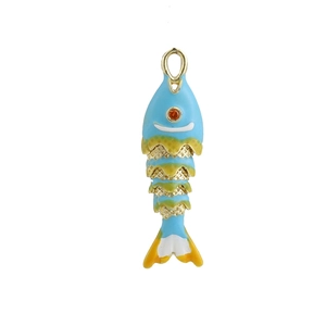 Détail macro du pendentif poisson en émail bleu ciel avec écailles dorées et gemme rouge