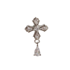 Detailed macro of a silver cross pendant featuring pear-cut and square zircon stones