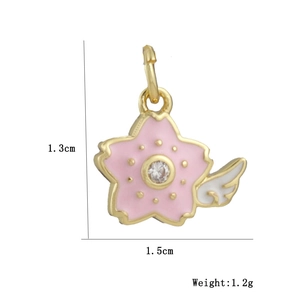 Macro detail of gold-plated cherry blossom pendant with pink enamel wing and white zircon