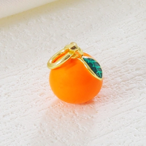 Detailed macro shot of an orange fruit charm with glossy finish and green leaf detail