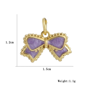 Macro detail of a purple enamel bow charm with gold plating and 1.5cm size markings