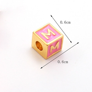 Detail der 0,6 cm großen rosa Emaille-Würfelperle mit goldenem Buchstaben M für DIY-Schmuck