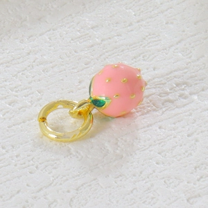 Macro shot of light pink strawberry enamel pendant with golden dots and green leaf detail
