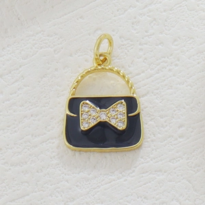 Macro detail of gold-plated handbag pendant with black enamel and zircon bow detail