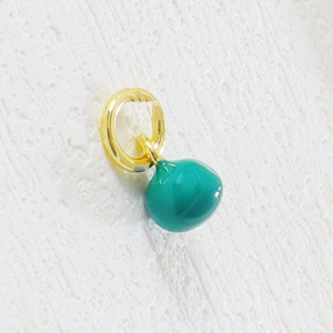 Macro detail of round teal enamel fruit charm with a polished gold ring for DIY jewelry
