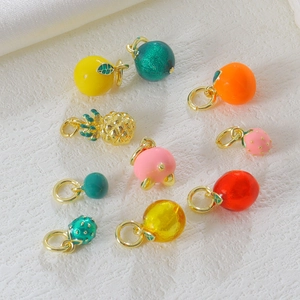 Flat lay of colorful enamel fruit charms including strawberry and lemon on stone tray