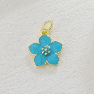 Detail of blue enamel flower pendant with gold plating and fine glitter accents
