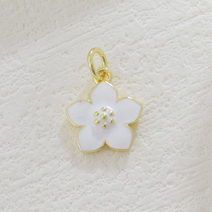 Macro shot of a cherry blossom pendant with white enamel petals and gold flower core
