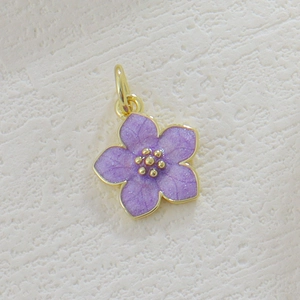 Macro shot of gold plated cherry blossom flower charm with purple enamel and zircon details