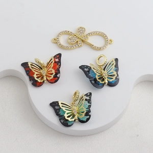 Detalle de colgantes de mariposa en oro de 18k con textura de mármol y cristales micro-pavé