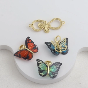 Vista macro de colgantes de mariposa coloridos y símbolo de infinito chapados en oro 18k