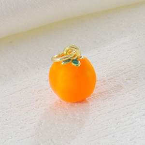 Close-up of small 18k gold plated orange fruit pendant with green leaf for DIY jewelry