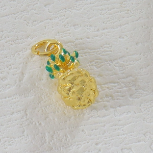 Detail view of a gold-plated pineapple pendant with green enamel and metal ring
