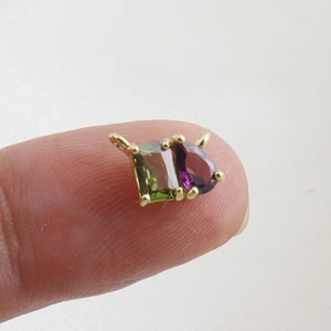Macro shot of a double stone pendant with green rectangle and purple teardrop zircon