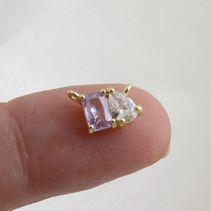Close-up of a 18k gold pendant with rectangular purple and teardrop zircon stones