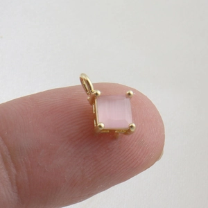 Detailed macro view of a tiny pink square gemstone pendant with 18k gold plating